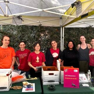 A group of people under a tent with a table with flyers about paleontology programs