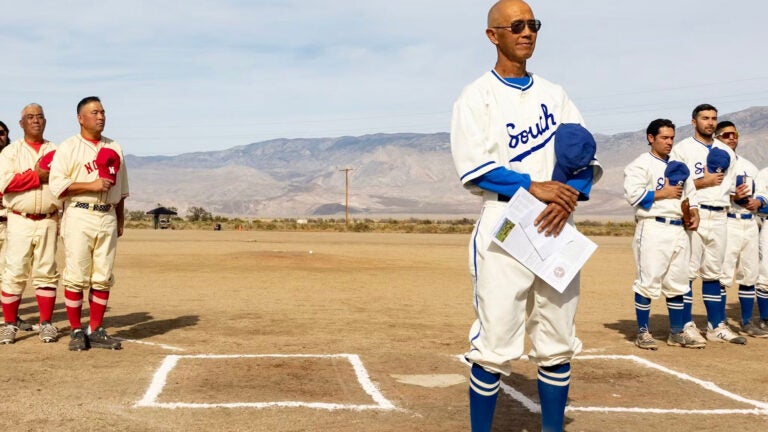 Baseball players wearing vintage 1940s-style uniforms stand lined up around a baseball diamond at former internment camp Manzanar.