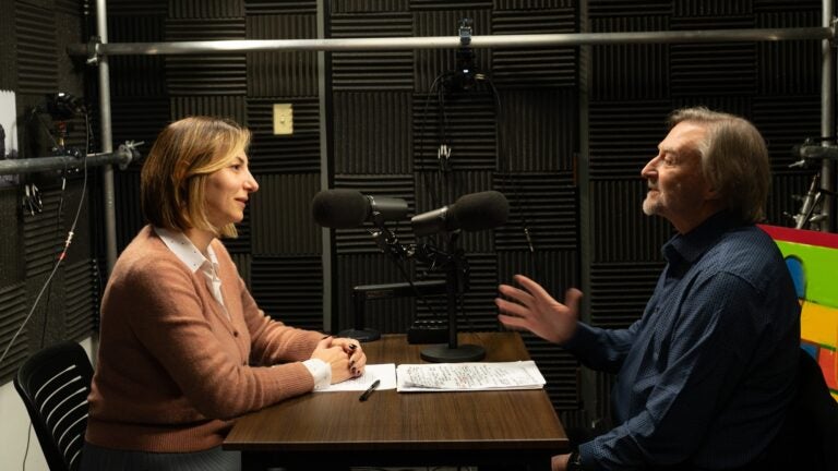 Shushan Karapetian and Peter Cowe sit opposite one another in a podcast studio