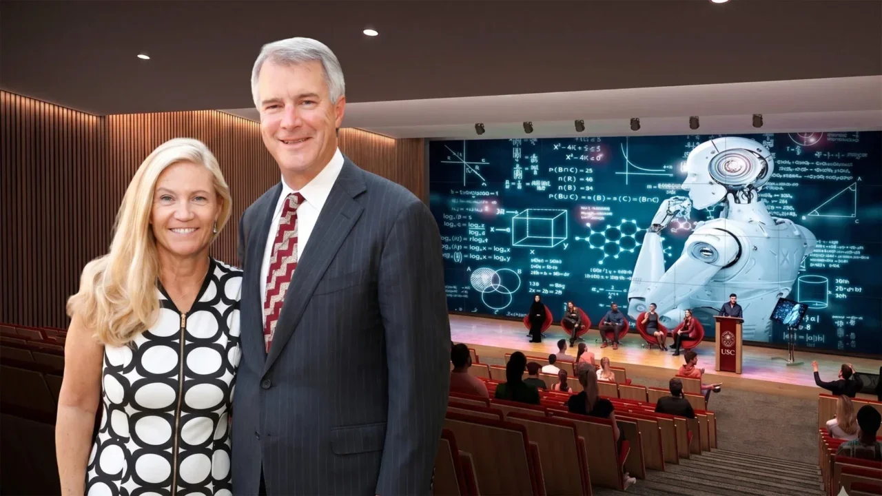 Photo of Mark and Mary Stevens standing in a classroom. A robot is pictured on a screen behind them.