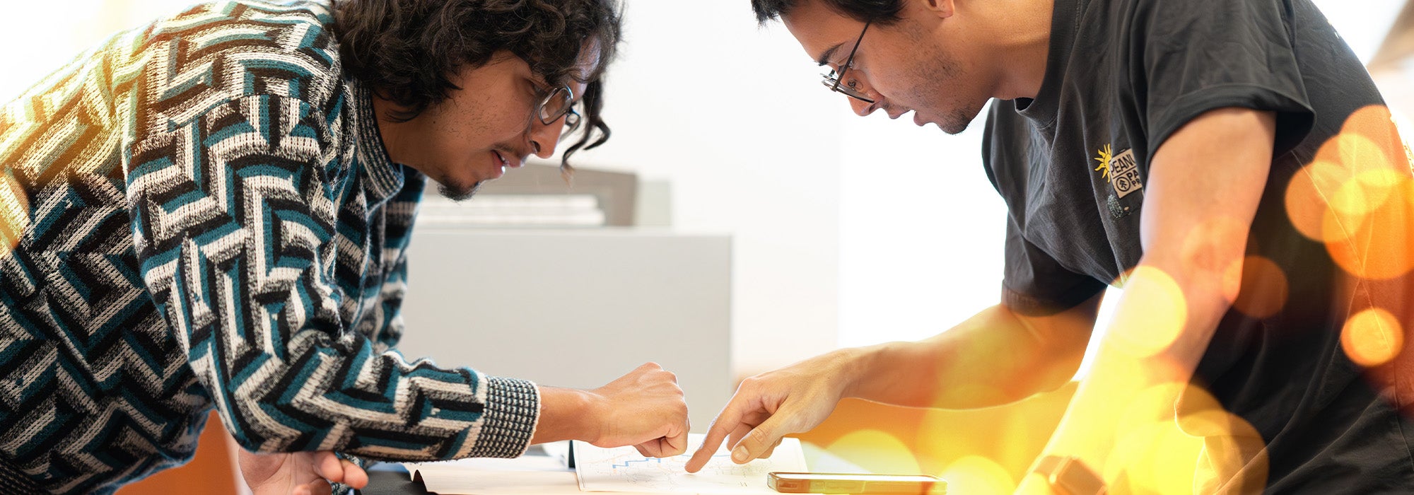 Two students pointing at paper on table