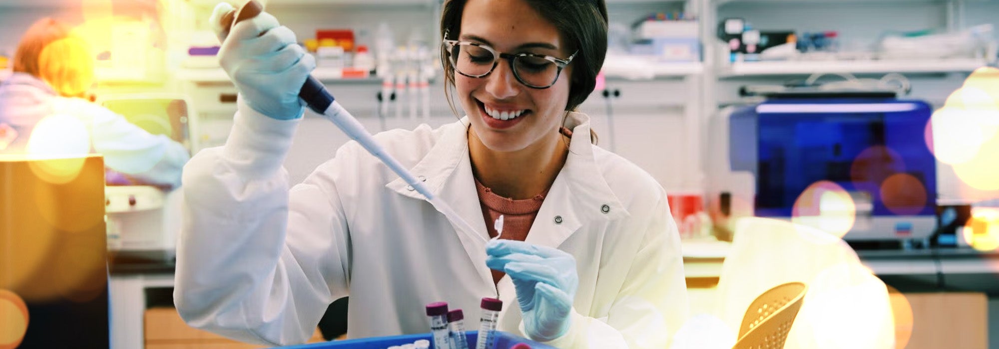 Woman in lab coat using micro pipette to fill vial in a lab setting