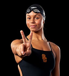 Jade Hannah makes the Fight On sign and wears a black USC swimsuit, black swim cap and goggles on her forehead.