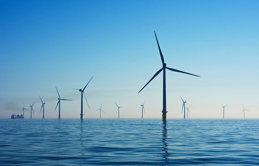 A photo of wind turbines over a body of water.