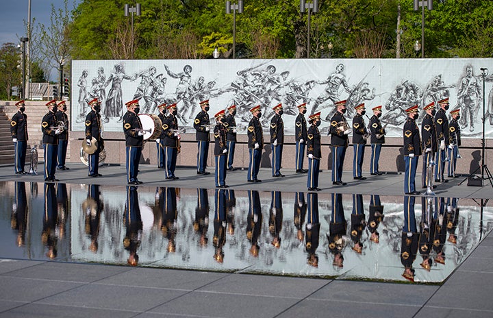 Group of soldiers stands in front of the memorial wall.