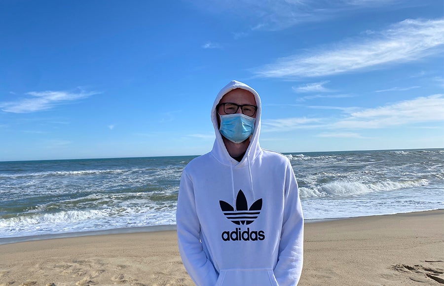 Photo of Jack Patton at the beach wearing a sweatshit and face mask