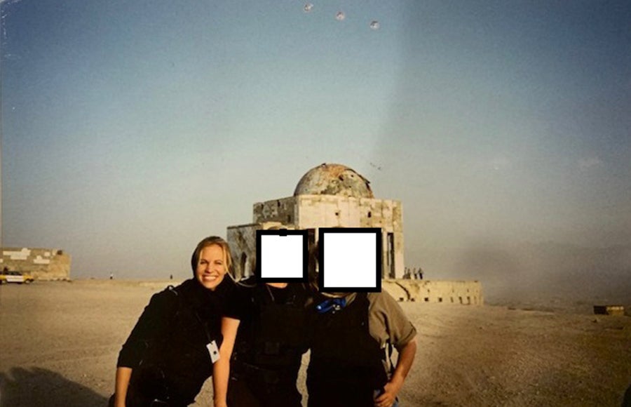 Photo of Tracy Walder in a CIA uniform with two uniformed colleagues whose faces have been obscured in a bleak location