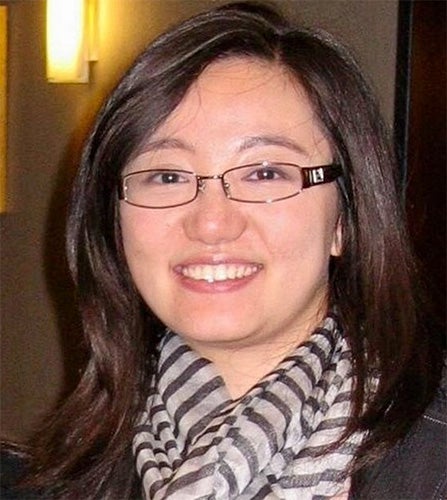 Portrait of Ying Liu smiling wearing glasses and a black jacket with a striped scarf