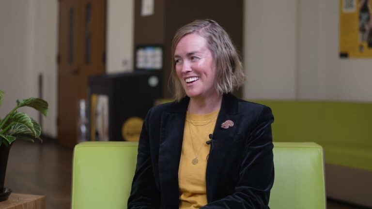 USC Environmental Studies Program director Jill Sohm, wearing a yellow shirt and black blazer, smiles as she speaks with Karla Heidelberg, who is seated off-camera