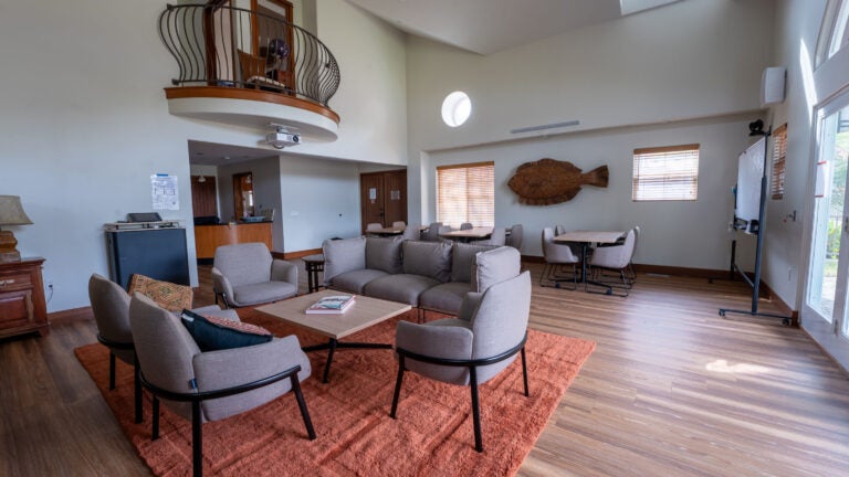 a double-height room with soft seating and low tables for meeting and conversations
