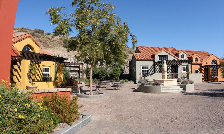 exterior of the Boone Center, which consists of Mediterranean revival townhome-style buildings arranged around a paved courtyard with a fountain in the center