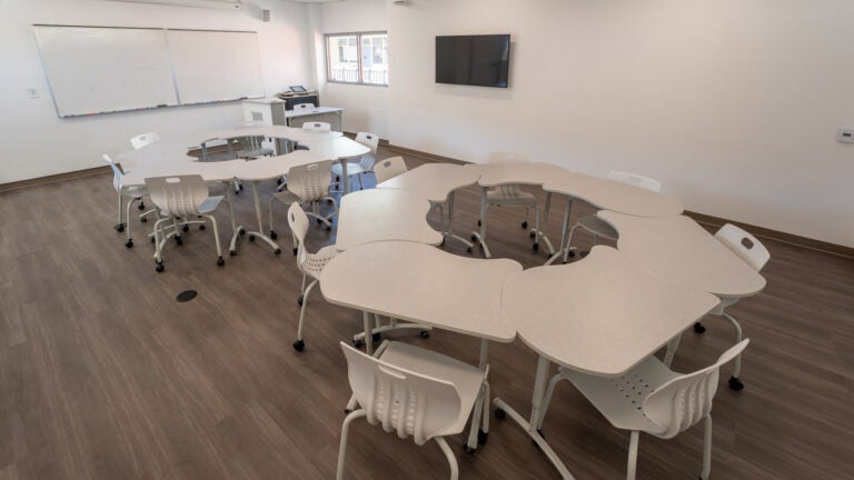 a medium-sized classroom, showing modular rolling tables and chairs arranged in two circles