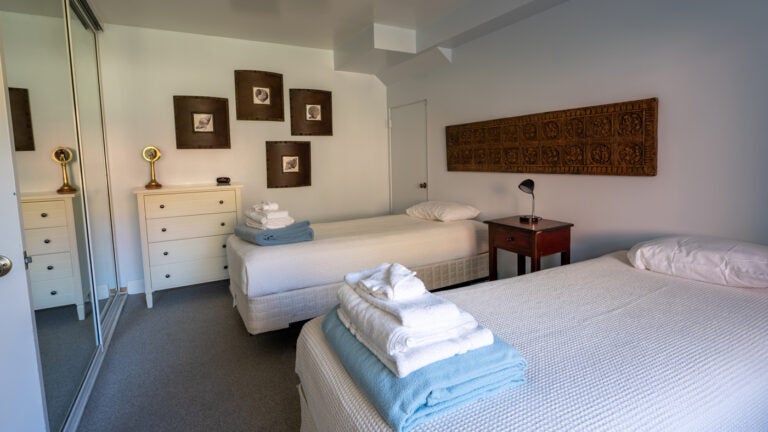 A bedroom with two twin beds covered in white blankets