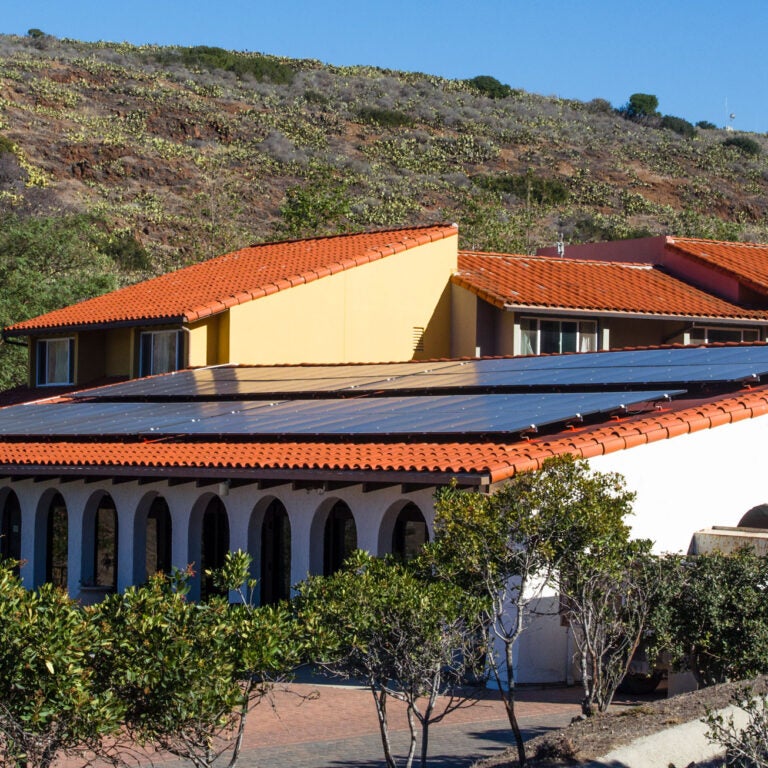 solar panels cover the roof of the WMSC dining hall, a one-story white stucco building with a colonnaded portico