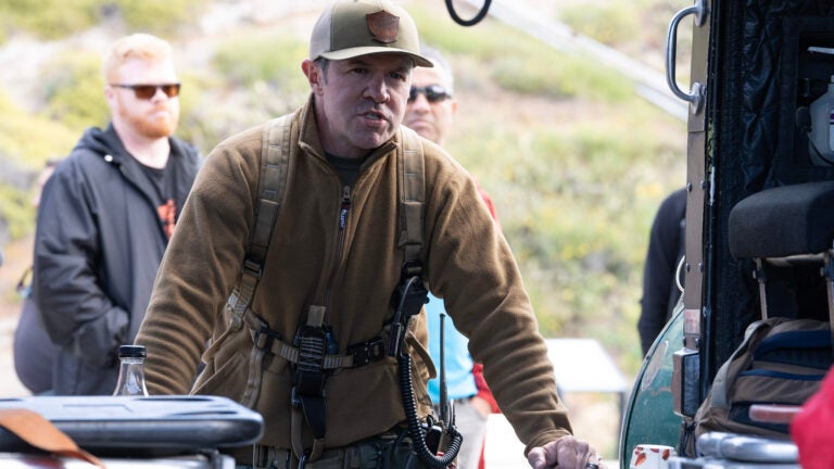 A sheriff leans into the open door of their helicopter while talking to people