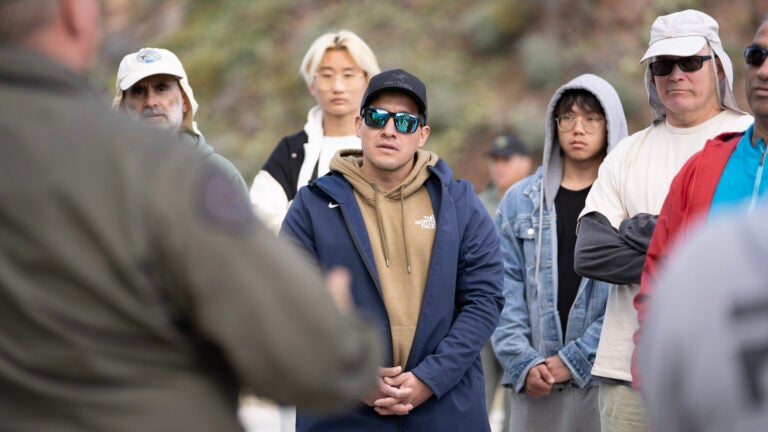 A group stands attentive while listening to a sheriff speak
