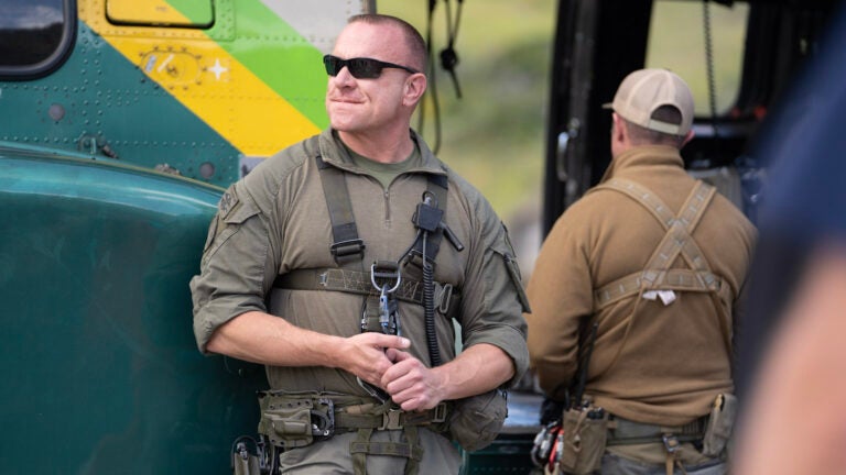 A sheriff stands by their helicopter while rubbing their hands together