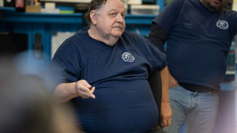 A hyperbaric chamber expert speaks to a crowd while sitting in a chair