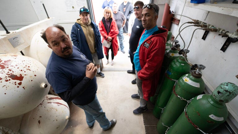 A group of people stand next to compressed gas tanks