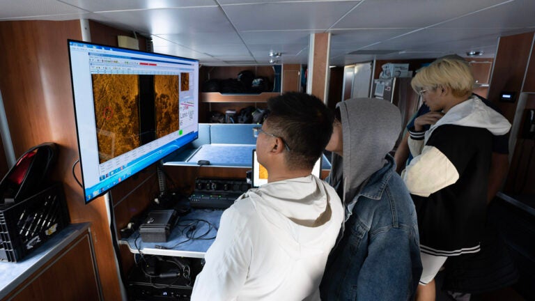 Students look at a screen on the lower level of a boat