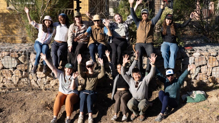 Students and faculty pose at the project site with their arms spread