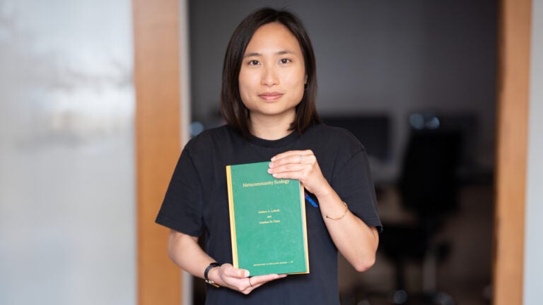 A student holds up a book titled 