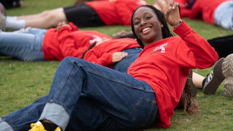 a smiling student, wearing a red shirt, holds up a 