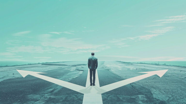 a person stands on an empty road with two arrows branching off to the left and right