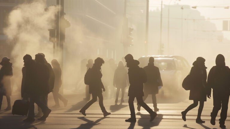 people and cars on a busy urban street with poor air quality