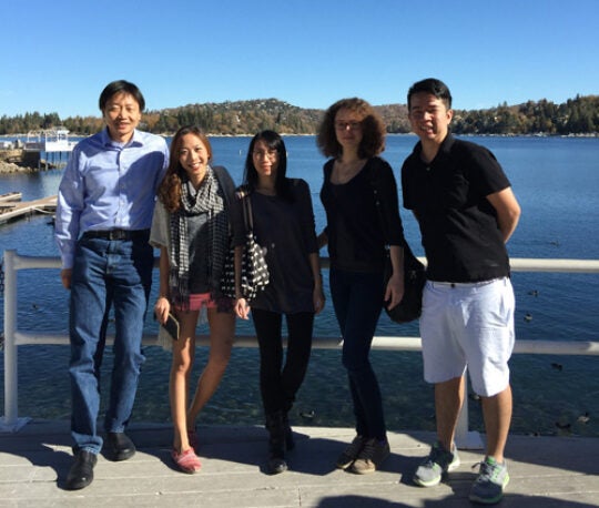 Group photo standing on a dock overlooking a lake and mountains in the background.